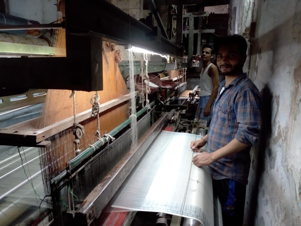 पीलीकोठ में पावरलूम मशीन पर चाइनीज रेशमी धागे से बनारसी साड़ी बुनता कारीगर।