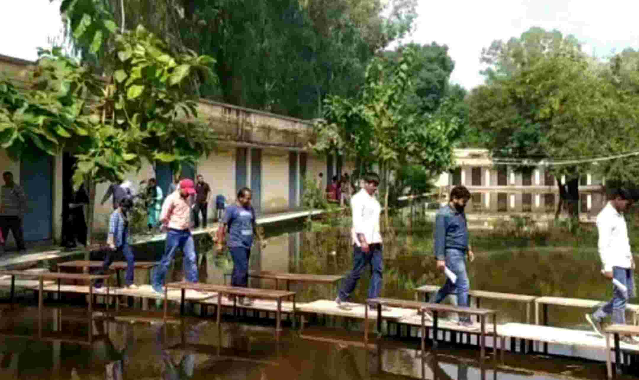 Pilibhit News : UP के पीलीभीत में परीक्षा केंद्र में जलभराव, बेंचों का बनाया पुल तब परीक्षा कक्ष में पहुंचे परीक्षार्थी